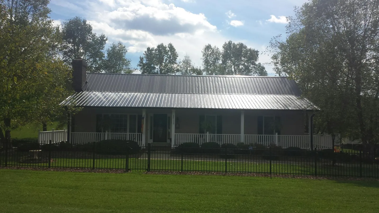 Gray metal roof on a brick ranch with a full width front porch in Barrington