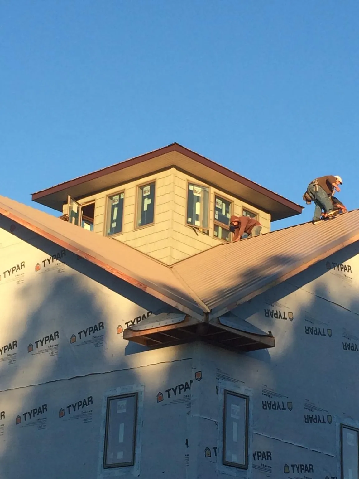 Roofers working around a rooftop cupola on a new metal roof at sunset — Roof Waterproofing in Barrington by Roofing Brothers